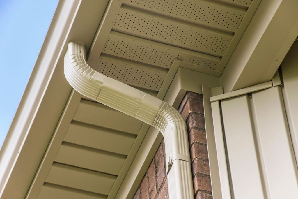 Close-up image of a beige rain gutter system installed on a residential home, showcasing the precise work of professional gutter installers in Calgary.